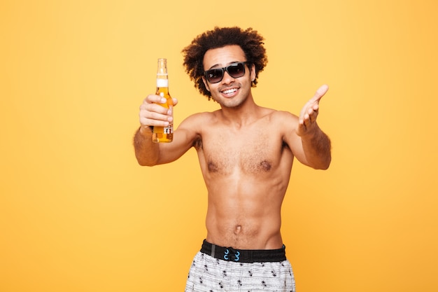 Free photo smiling young african man drinking beer