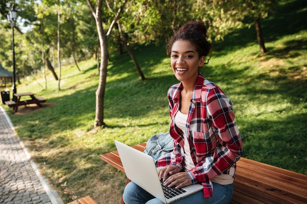 公園の屋外に座っている笑顔の若いアフリカ人女性