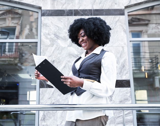 Smiling young african young businesswoman checking the paper on clipboard