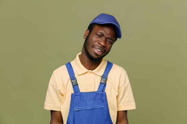 Smiling young africanamerican cleaner male in uniform with gloves isolated on green background