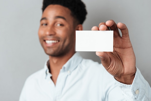 Smiling young afro american guy showing blank business card