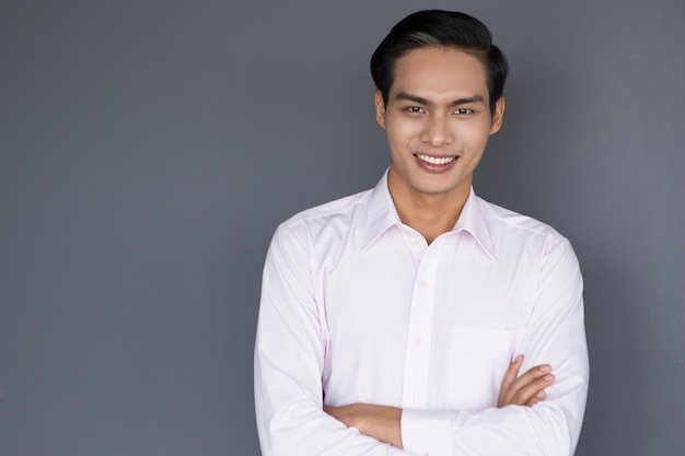 Foto gratuita sorridente giovane imprenditore asiatico con le braccia incrociate