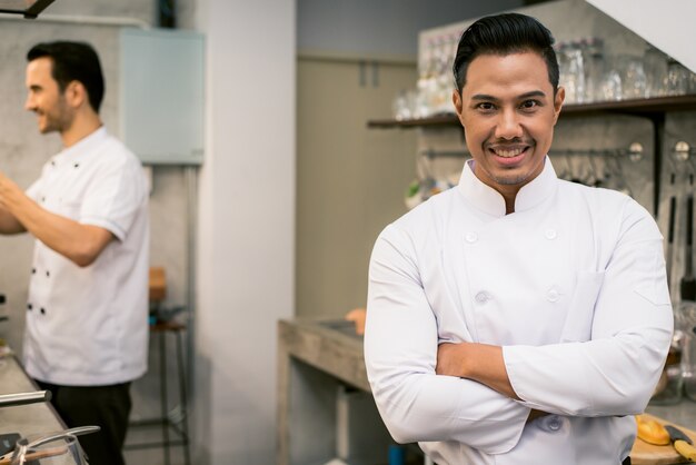 Smiling young asian chef in the kitchen interior of the restaurant. Vintage filtered image.