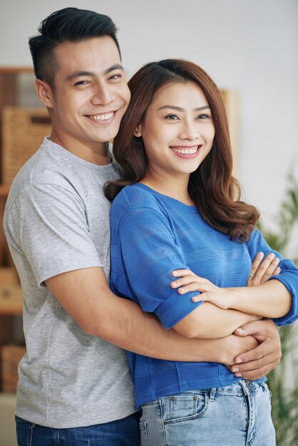 Улыбающиеся молодые азиатские пары стоя и обниматься в помещении
