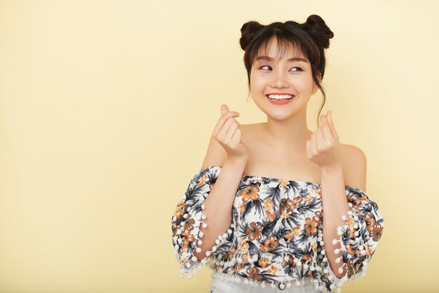 Smiling young Asian woman in bare shoulder blouse posing in studio