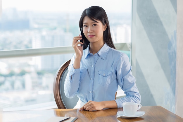 Smiling Young Asian Woman in Cafe Calling on Phone