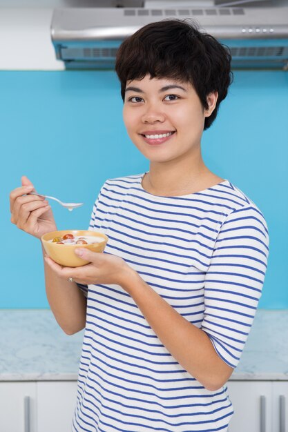 토마토 Raita를 먹고 웃는 젊은 아시아 여성