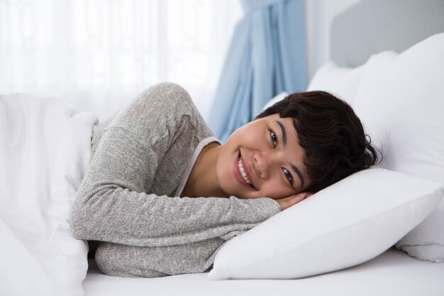 Smiling Young Asian Woman Lying in Bed