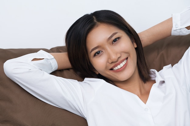 Smiling Young Asian Woman Lying on Cushion