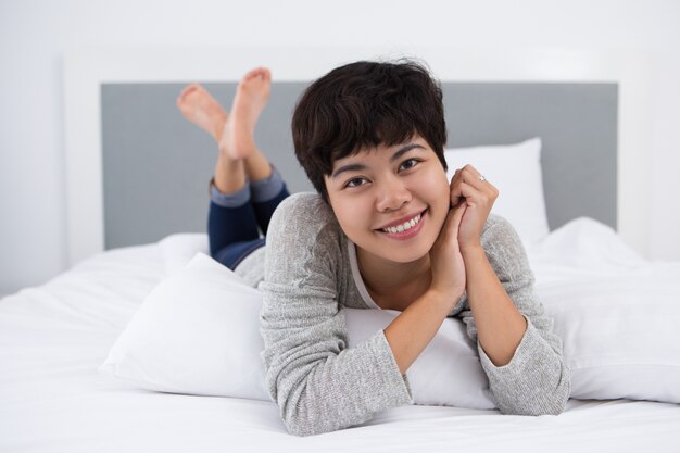 침대에서 쉬고 웃는 젊은 아시아 여성