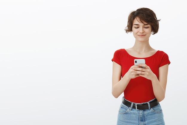 스마트 폰에서 데이트 앱을 사용하여 휴대 전화에 문자 메시지 젊은 매력적인 여성 미소 짓기