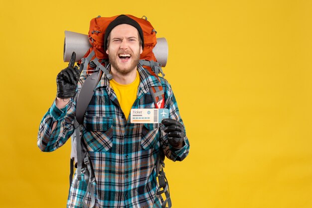 Free photo smiling young backpacker with black hat holding airplane ticket