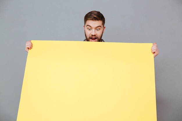 Smiling young bearded man holding blank board