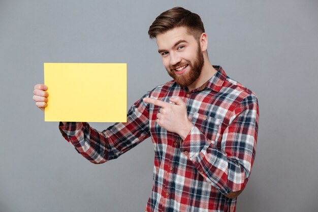 Smiling young bearded man holding blank paper