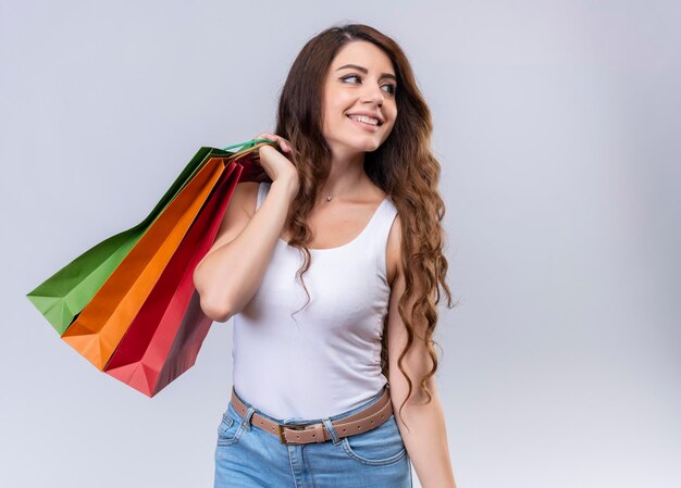 Smiling young beautiful girl holding shopping bags on shoulder looking at right side  with copy space