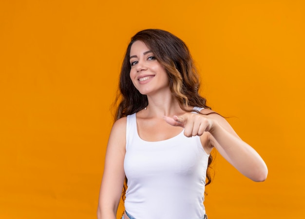 Smiling young beautiful girl pointing  on isolated orange space with copy space