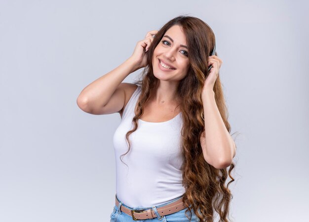 Smiling young beautiful girl wearing headphones putting hands on them 