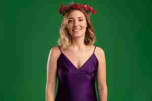 Foto gratuita sorridente giovane bella ragazza che indossa un abito viola con corona isolata su sfondo verde on