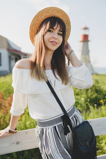 Smiling young beautiful stylish woman, spring summer fashion trend, boho style, straw hat, countryside weekend, sunny, black purse