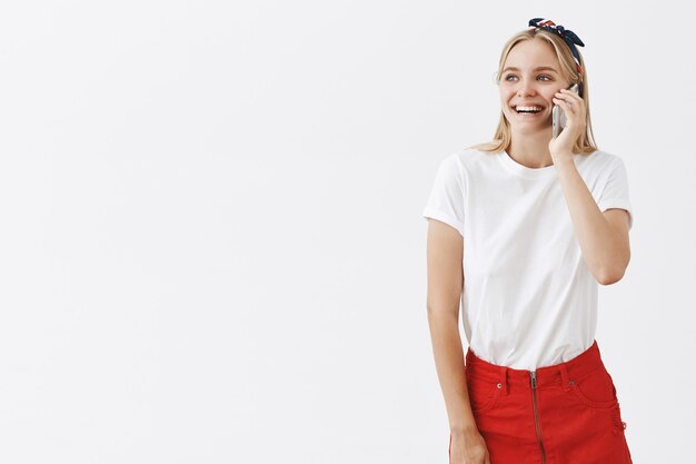 Smiling young blond girl posing against the white wall