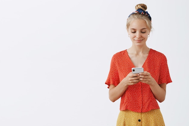 Smiling young blond girl posing against the white wall