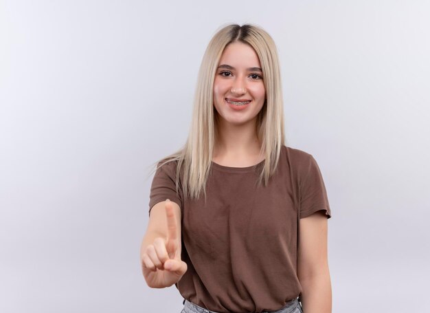 Smiling young blonde girl in dental braces with raised finger on isolated white space with copy space