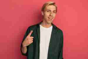 Free photo smiling young blonde guy wearing green t-shirt point at up