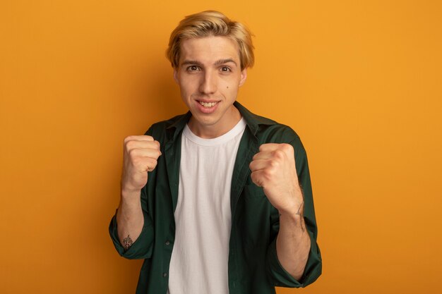 Smiling young blonde guy wearing green t-shirt standing in fighting pose