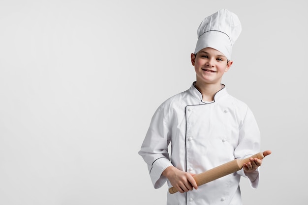 Smiling young boy holding rolling pin with copy space