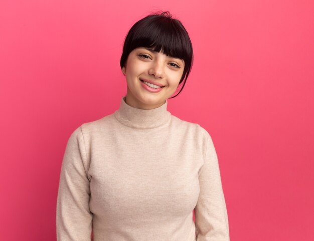 コピースペースとピンクの壁に分離された若いブルネット白人の女の子の笑顔