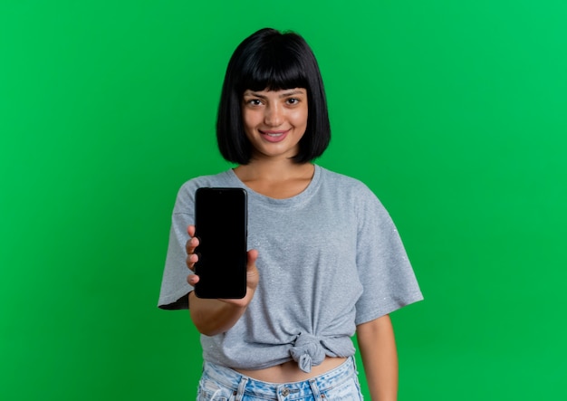 Smiling young brunette caucasian woman holds phone