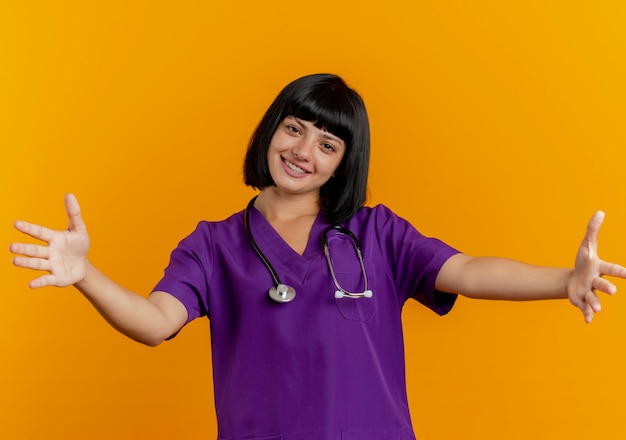 Sorridente giovane dottoressa bruna in uniforme con stetoscopio