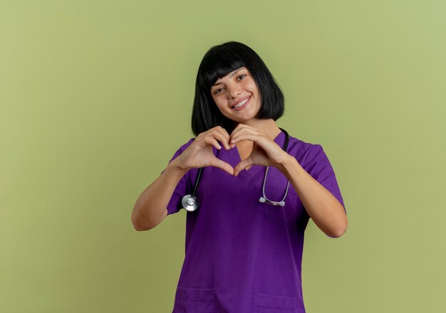 Smiling young brunette female doctor in uniform with stethoscope