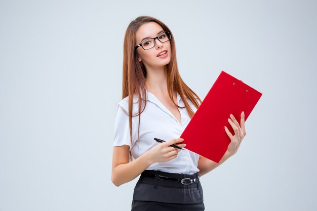 Smiling young business woman in glasses with pen and tablet for notes on a gray background