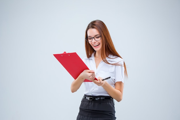 Smiling young business woman in glasses with pen and tablet for notes on a gray background