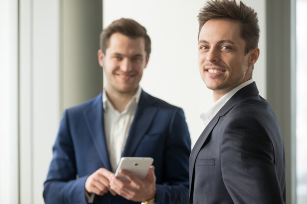 Smiling young businessman looking at camera, application develop