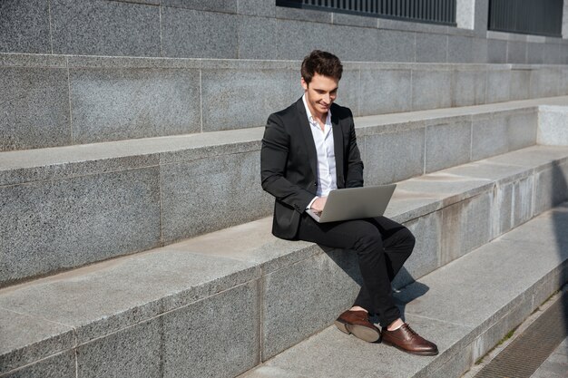 Smiling young businessman sitting outdoors.