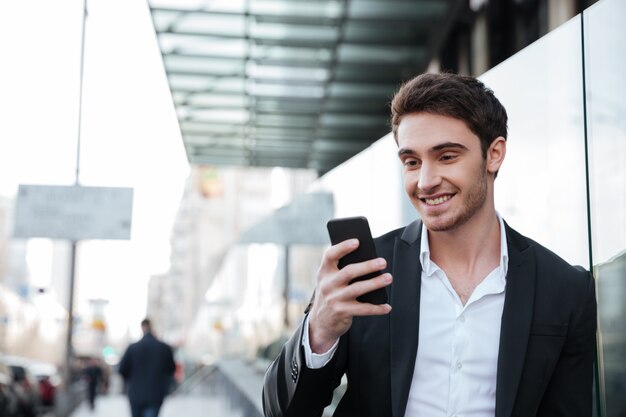 Smiling young businessman walking near business center.