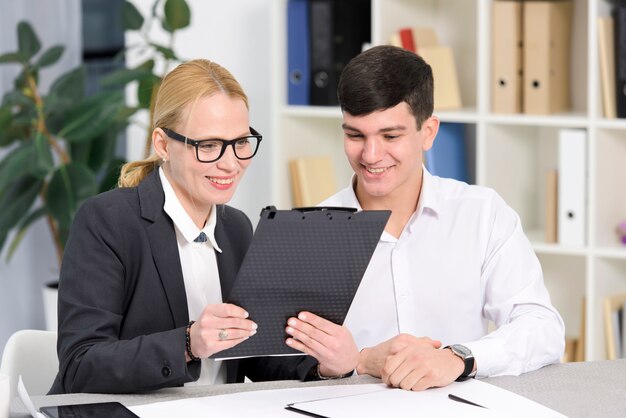 笑顔の若い実業家と実業家のオフィスでデジタルタブレットを見て