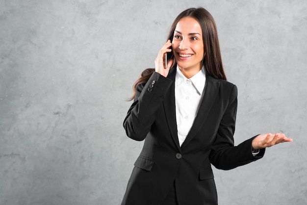 Smiling young businesswoman talking on cellphone gesturing