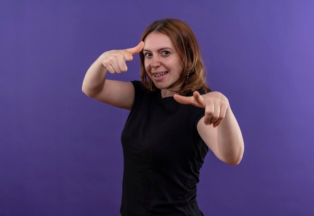 Smiling young casual woman doing you gesture on isolated purple space with copy space