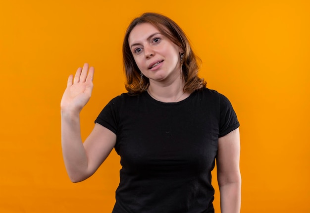 Smiling young casual woman gesturing hi on isolated orange space