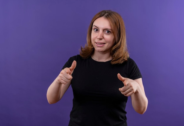 Smiling young casual woman pointing  on isolated purple space with copy space