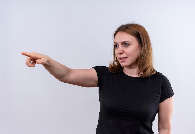 Smiling young casual woman pointing and looking at left side on isolated white space