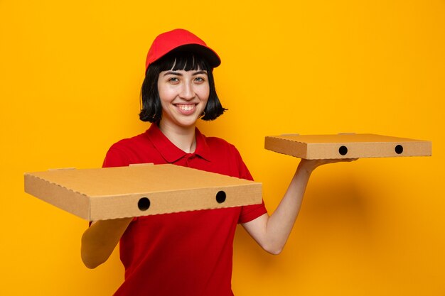 Smiling young caucasian delivery girl holding pizza boxes on hands