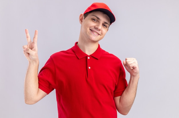 拳を保ち、勝利のサインを身振りで示す赤いシャツを着た若い白人配達人の笑顔