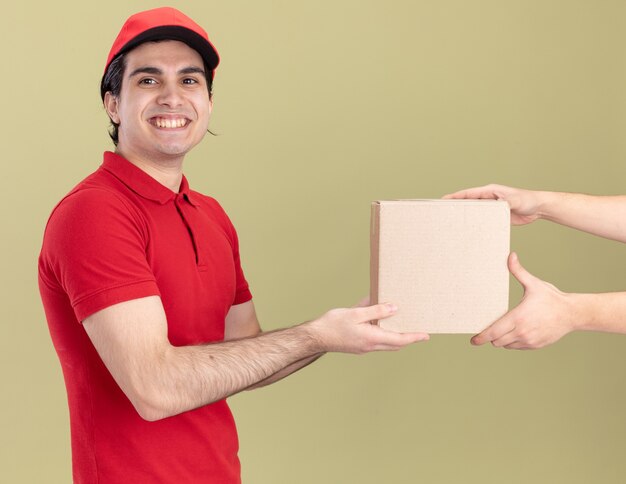 Smiling young caucasian delivery man in red uniform and cap 