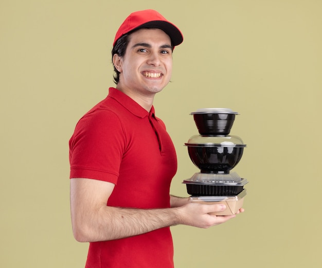 Smiling young caucasian delivery man in red uniform and cap 