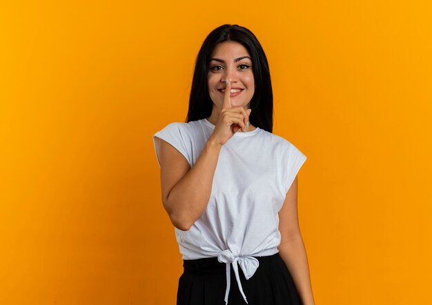 Smiling young caucasian girl gestures silence sign 