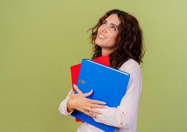 Smiling young caucasian girl holds file folders looking up 